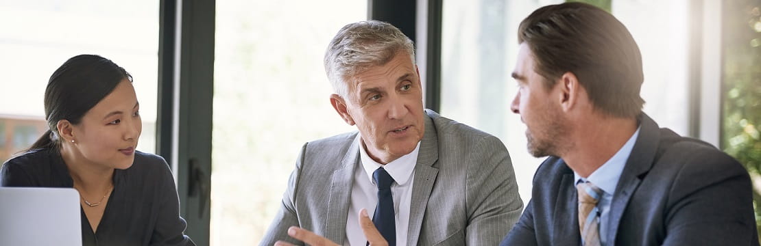 Three business professionals seated together and engaged in conversation